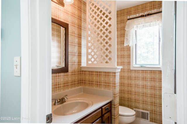 bathroom featuring toilet, visible vents, tile walls, and vanity