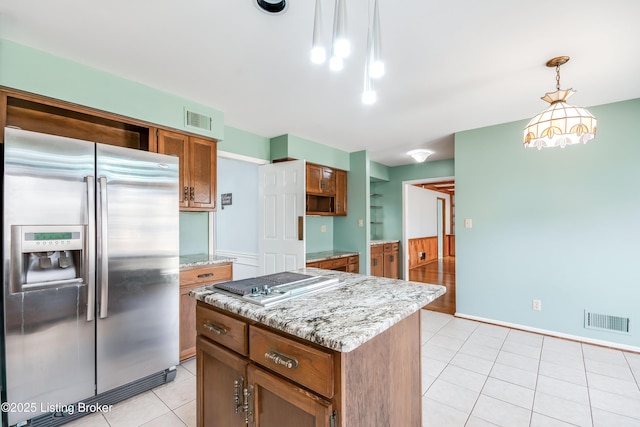 kitchen with visible vents, brown cabinetry, a center island, stainless steel appliances, and pendant lighting