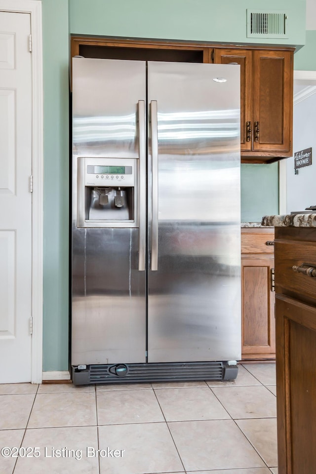 kitchen featuring brown cabinetry, visible vents, stainless steel fridge with ice dispenser, and light tile patterned floors