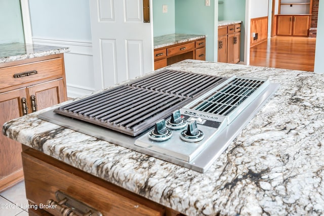 interior details with stainless steel gas stovetop, light stone counters, and brown cabinets