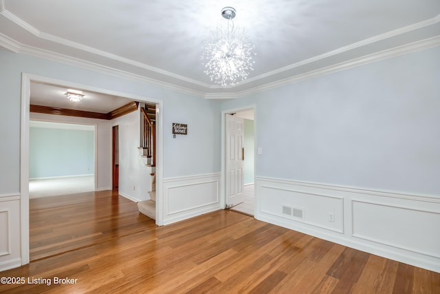 spare room featuring stairway, wood finished floors, visible vents, and a notable chandelier