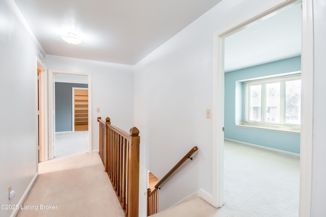 corridor featuring light carpet, visible vents, an upstairs landing, and baseboards