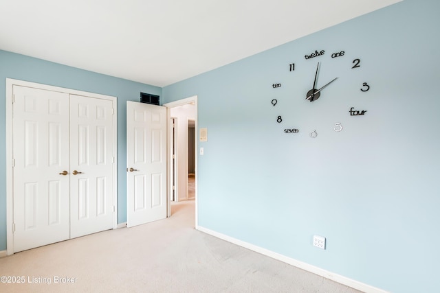 unfurnished bedroom with carpet, a closet, and baseboards