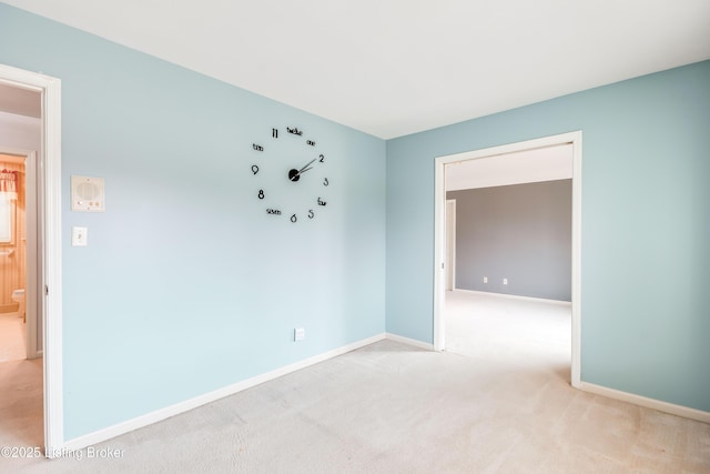 spare room with baseboards and light colored carpet