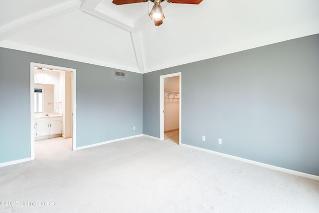 unfurnished bedroom with light colored carpet, a walk in closet, visible vents, and baseboards