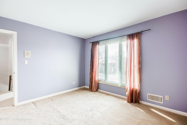 spare room with baseboards, visible vents, and light colored carpet