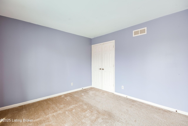 carpeted spare room featuring baseboards and visible vents