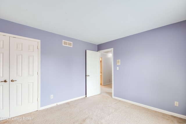 unfurnished bedroom featuring light colored carpet, a closet, visible vents, and baseboards