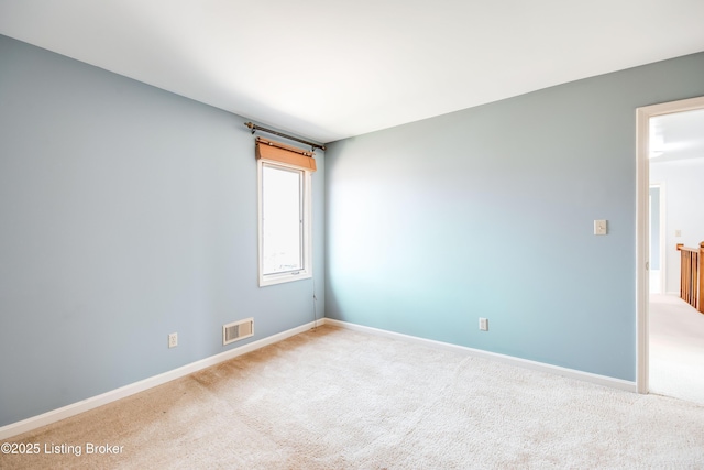 carpeted spare room with visible vents and baseboards