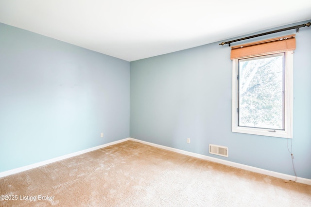 empty room with carpet, visible vents, and baseboards