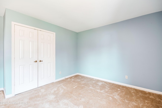 unfurnished bedroom featuring light carpet, a closet, and baseboards