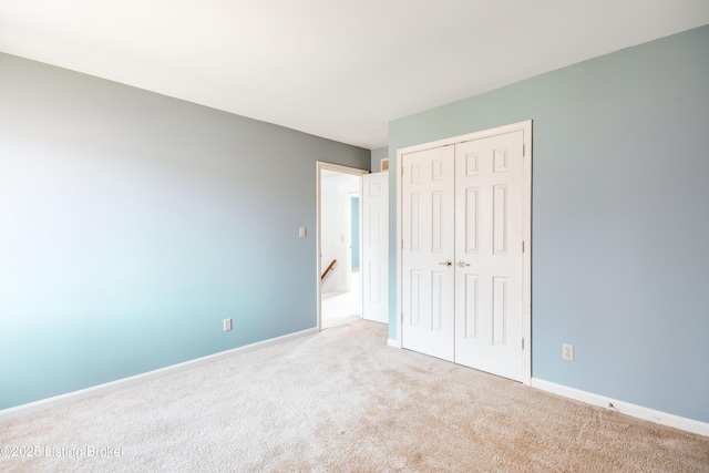 unfurnished bedroom with a closet, light carpet, and baseboards