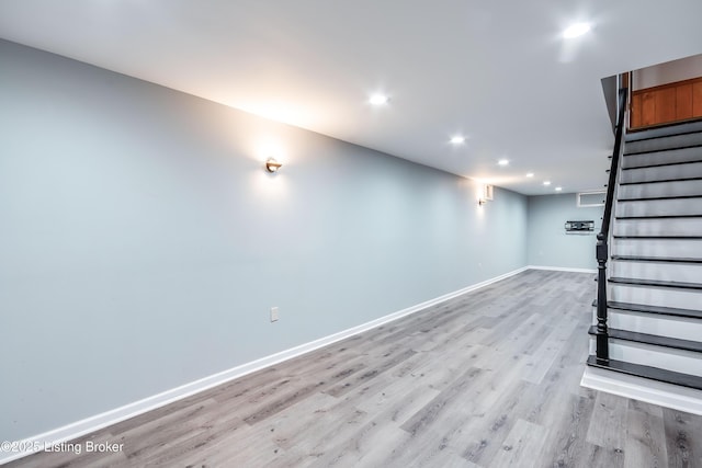 finished below grade area with light wood-type flooring, recessed lighting, baseboards, and stairs