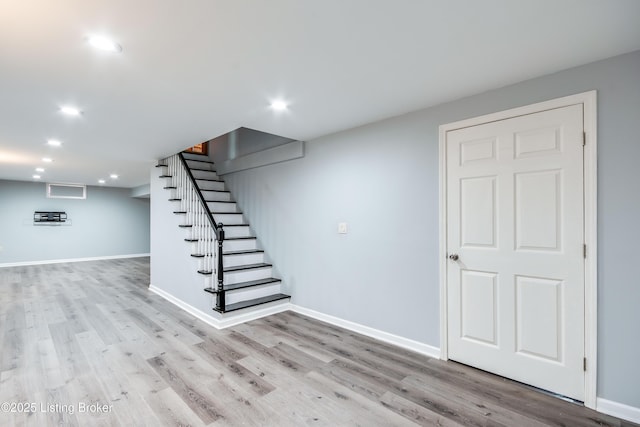 finished below grade area featuring light wood-type flooring, baseboards, stairway, and recessed lighting