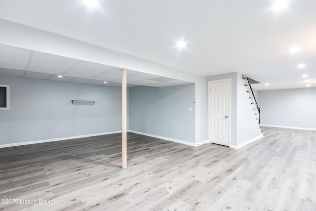 finished basement featuring light wood finished floors, recessed lighting, a paneled ceiling, and baseboards