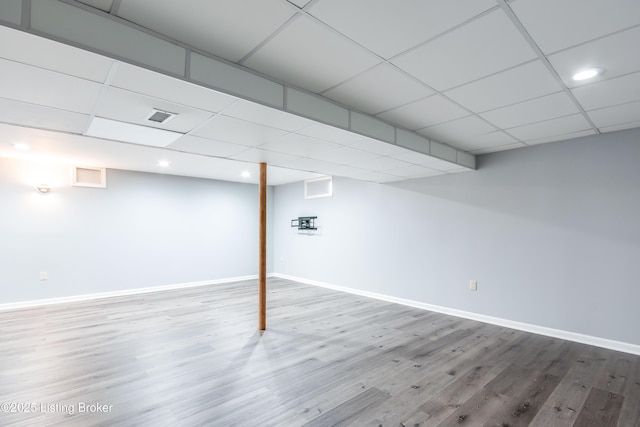 finished below grade area with a paneled ceiling, visible vents, and baseboards