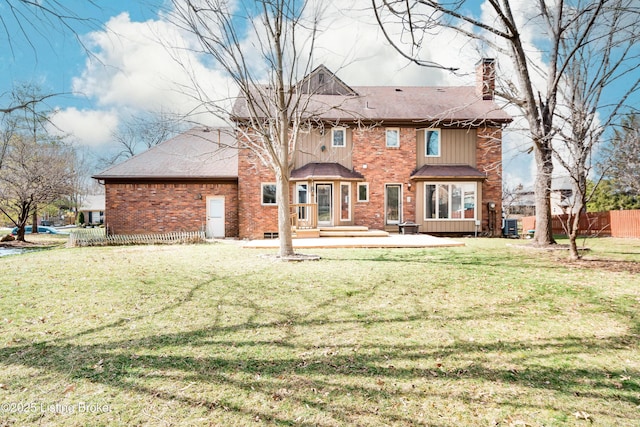 rear view of property featuring brick siding, a chimney, fence, and a lawn