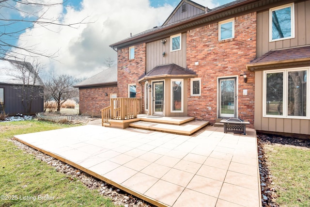 back of property featuring a fire pit, brick siding, board and batten siding, and a patio area