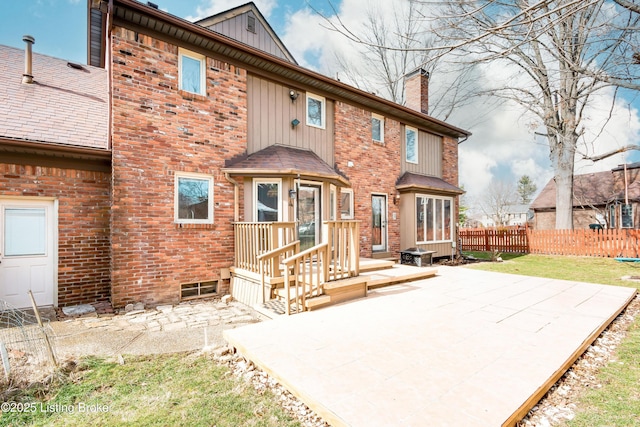 rear view of property with brick siding, a patio, a chimney, board and batten siding, and fence