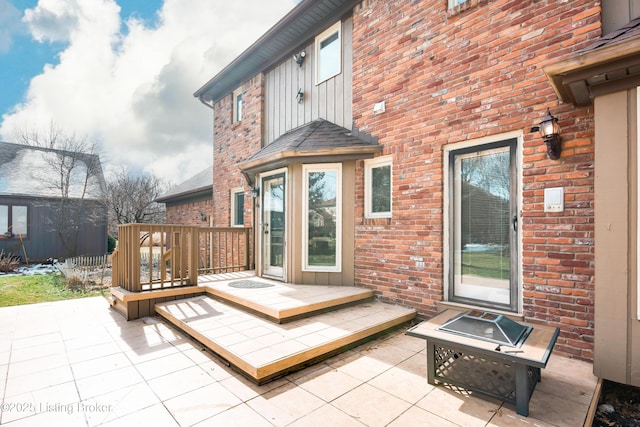 wooden terrace with an outdoor fire pit and a patio