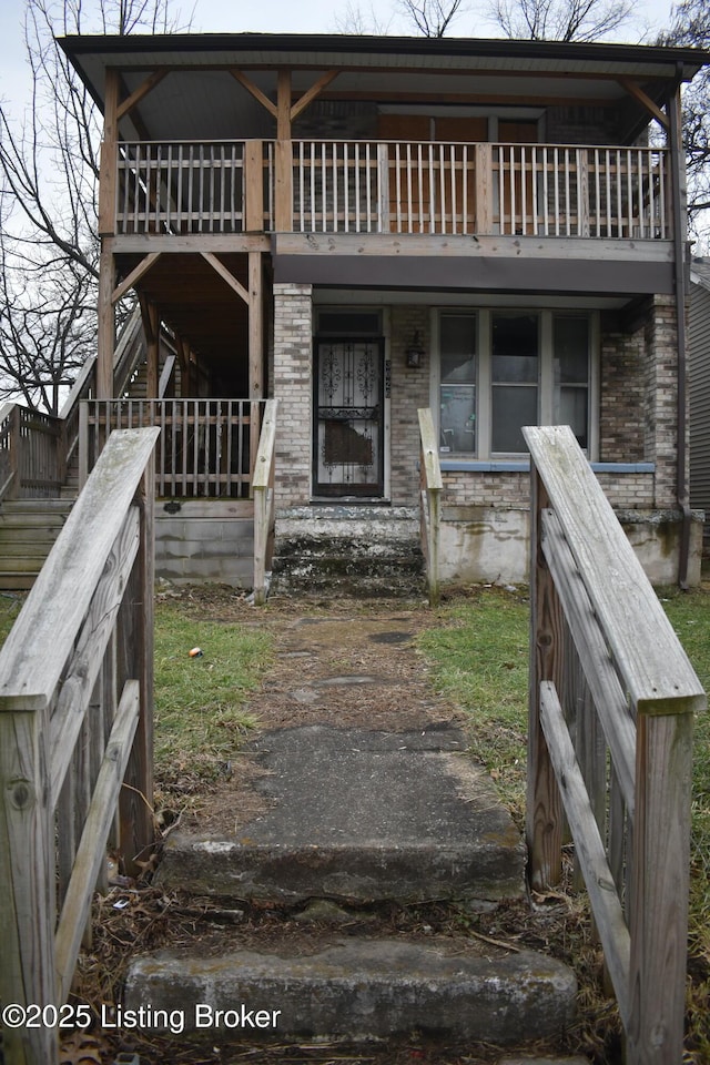 view of front of home featuring brick siding and a balcony