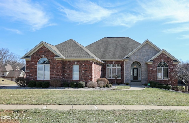 view of front of property featuring stone siding, brick siding, a front yard, and a shingled roof