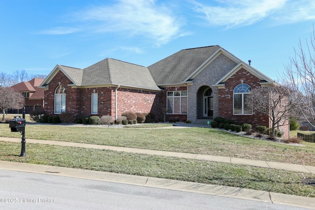 traditional-style home featuring a shingled roof, a front yard, and brick siding