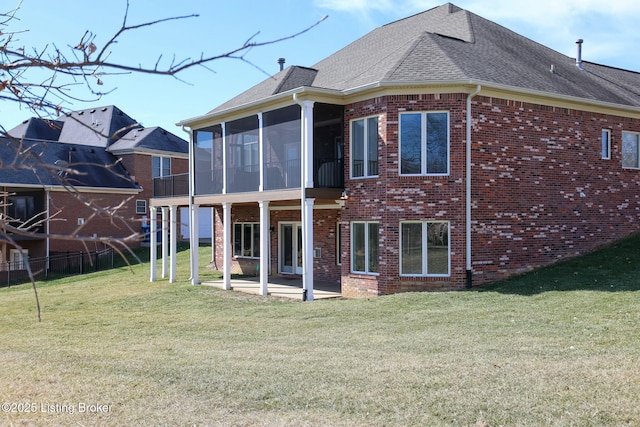 back of house with brick siding, a yard, a shingled roof, a sunroom, and a patio area