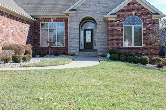 property entrance with a shingled roof, brick siding, and a lawn