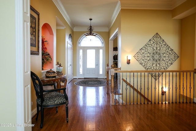 foyer entrance with crown molding, baseboards, and wood finished floors