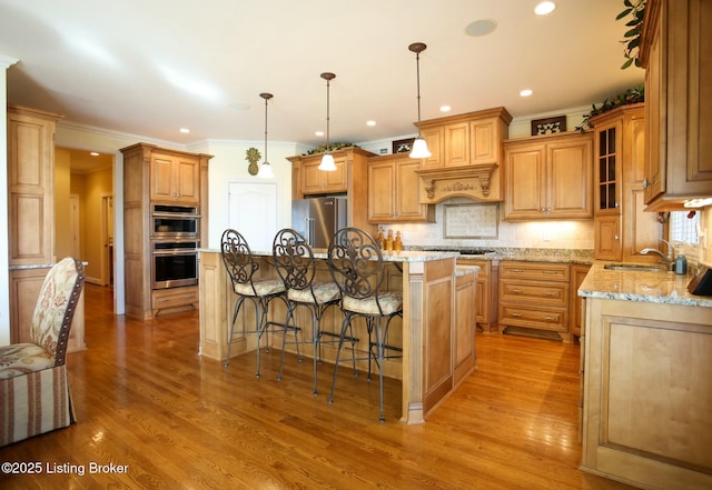 kitchen featuring a kitchen breakfast bar, light stone countertops, stainless steel appliances, light wood-type flooring, and backsplash