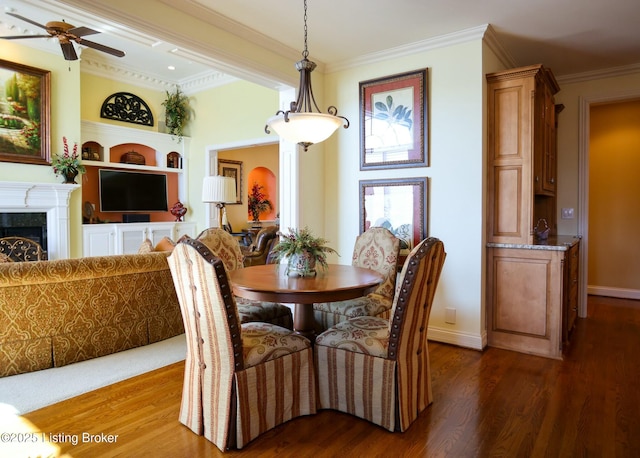 dining room with dark wood-style flooring, a fireplace, and crown molding