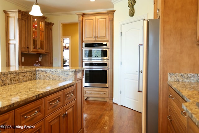 kitchen featuring light stone counters, dark wood-style flooring, stainless steel appliances, glass insert cabinets, and ornamental molding