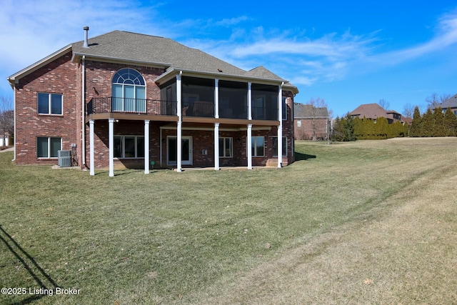 back of property featuring brick siding, a shingled roof, a lawn, central AC unit, and a sunroom