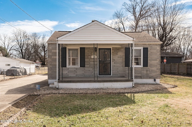 bungalow with stone siding, covered porch, roof with shingles, and fence