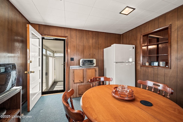 dining room featuring a toaster, carpet flooring, and wooden walls