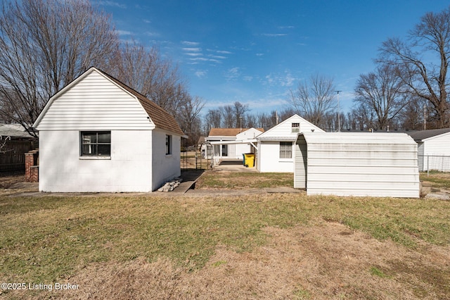 exterior space with a gambrel roof, fence, an outdoor structure, and a yard