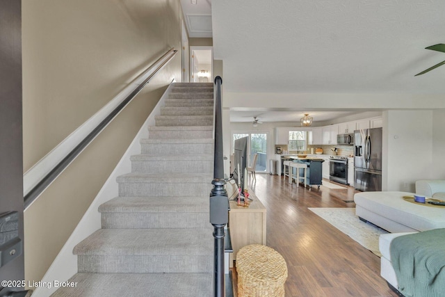 stairway with a ceiling fan and wood finished floors