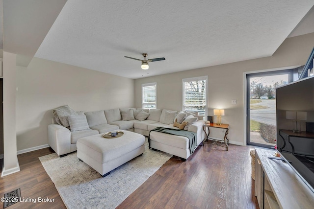 living room featuring dark wood-style floors, a textured ceiling, and baseboards