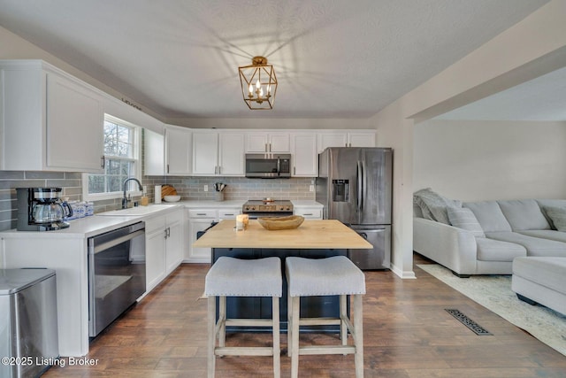 kitchen featuring visible vents, dark wood-style floors, open floor plan, stainless steel appliances, and a sink