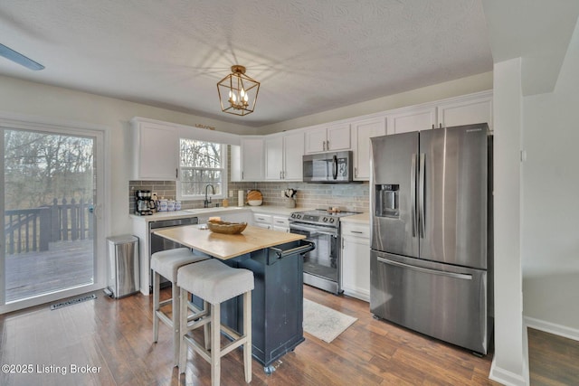 kitchen with stainless steel appliances, dark wood-type flooring, light countertops, and white cabinets