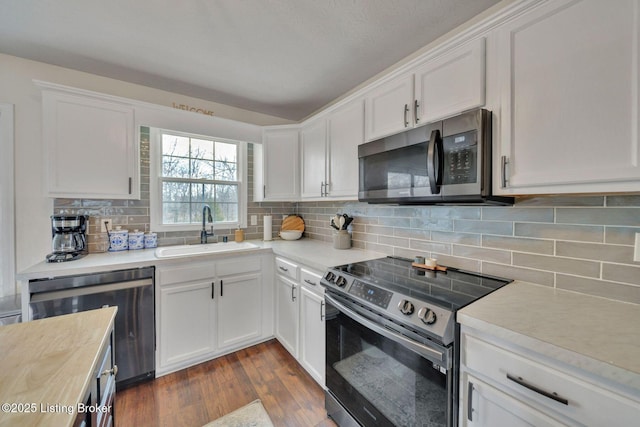 kitchen featuring stainless steel appliances, light countertops, white cabinetry, and a sink