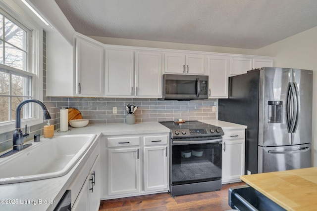 kitchen featuring stainless steel appliances, tasteful backsplash, light countertops, white cabinetry, and a sink