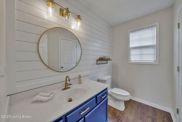 bathroom featuring toilet, baseboards, wood finished floors, and vanity