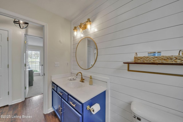 bathroom with baseboards, vanity, toilet, and wood finished floors