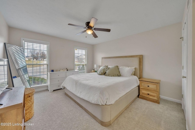 bedroom with ceiling fan, baseboards, and light colored carpet