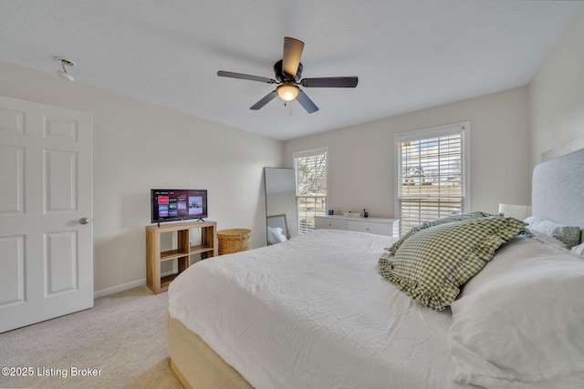 carpeted bedroom with ceiling fan and baseboards