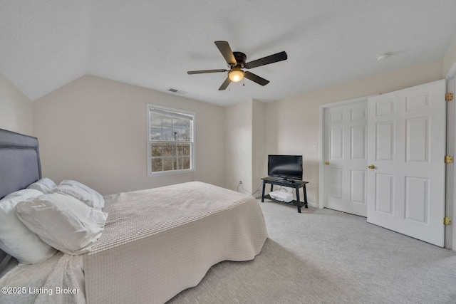 bedroom featuring visible vents, lofted ceiling, ceiling fan, a textured ceiling, and carpet floors