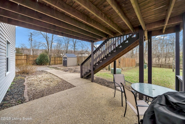 view of patio / terrace featuring a storage shed, a fenced backyard, a grill, an outdoor structure, and outdoor dining space