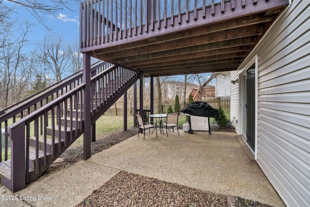 view of patio featuring outdoor dining area, fence, grilling area, and stairs